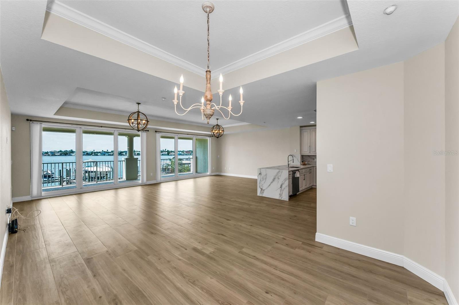 ..Dining Area With High Tray Ceilings.  1100 Sq Ft  Great Room - and Boca Ciega Bay in Background. New Wall Finish Sherman Williams - SW 9109 Natural  Linen / Satin. New Flooring - Woodville Natural Wood Plank Porcelain Tile.