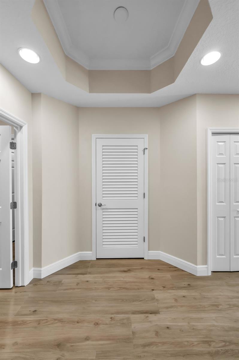 .. Master Suite Entrance off Great Room . Master / Primary  Bath to Left Doorway - Waterfront Master/ Primary Bedroom to Right . New Flooring - Woodville Natural Wood Plank Porcelain Tile....  One of Two A/C systems Through  Louvered 2 Panel Door. Don't forget the New Wall Finish thru - out the Entire Residence.