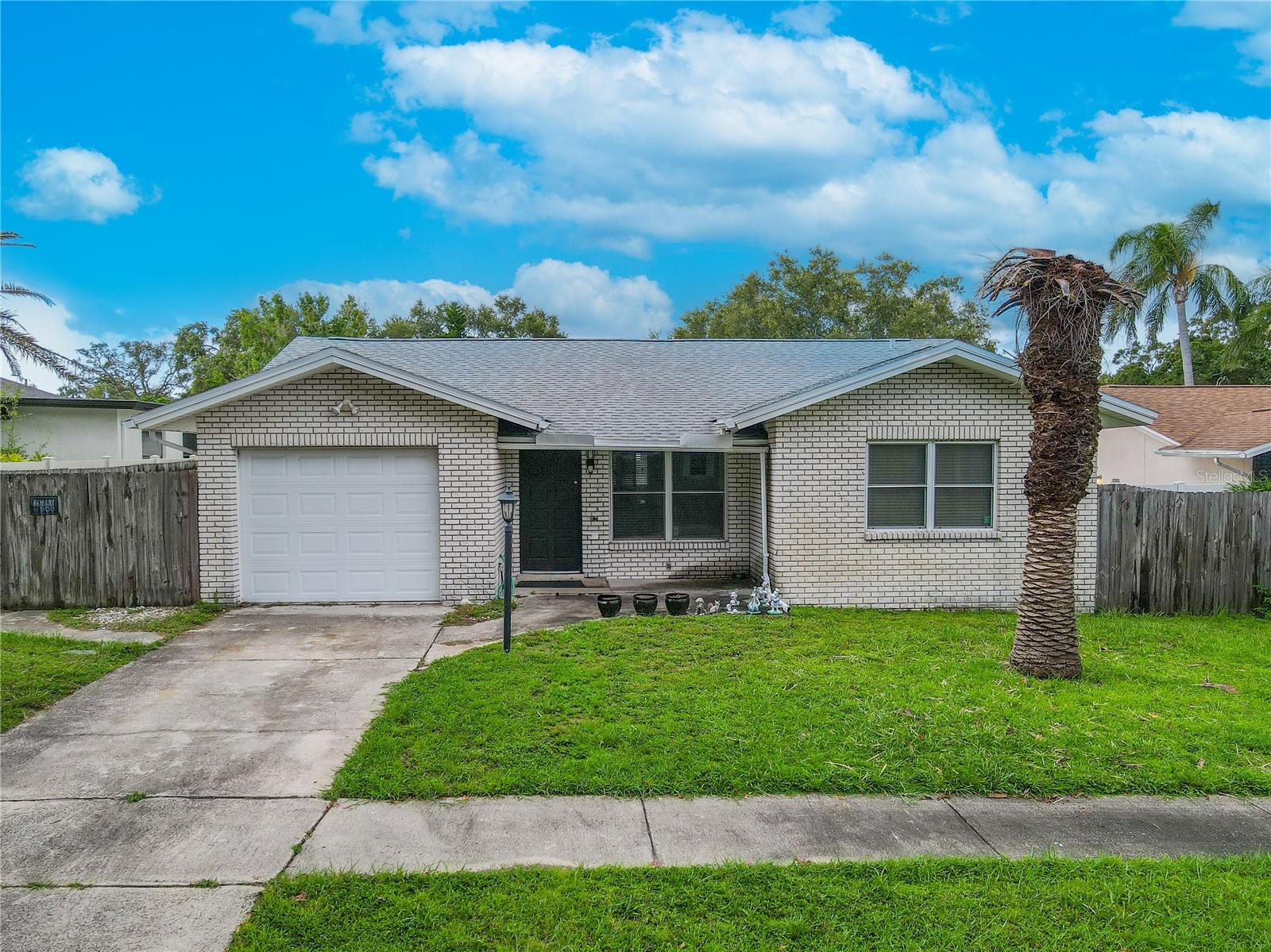 This 2-bedroom, 2-bath home features a clean, low-maintenance exterior with light brick construction and a welcoming covered entry. A single-car garage and wide driveway provide ample parking, while the fenced side and backyard offer privacy.