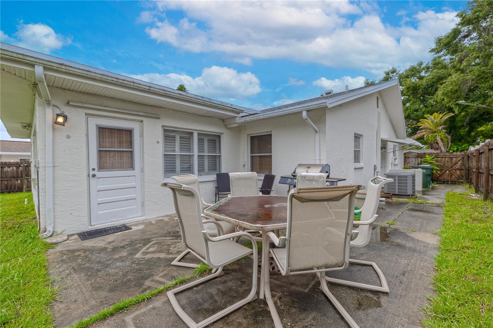 Fenced backyard with a concrete patio, perfect for outdoor dining and entertaining. Offers space for seating, a grill, and easy access to the home through a rear entry door.