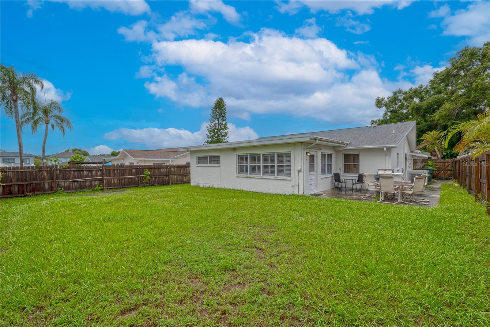 Spacious fenced backyard with plenty of room for outdoor activities, gardening, or future customization. Features a concrete patio area for seating and dining, with direct access to the home for easy indoor-outdoor living.
