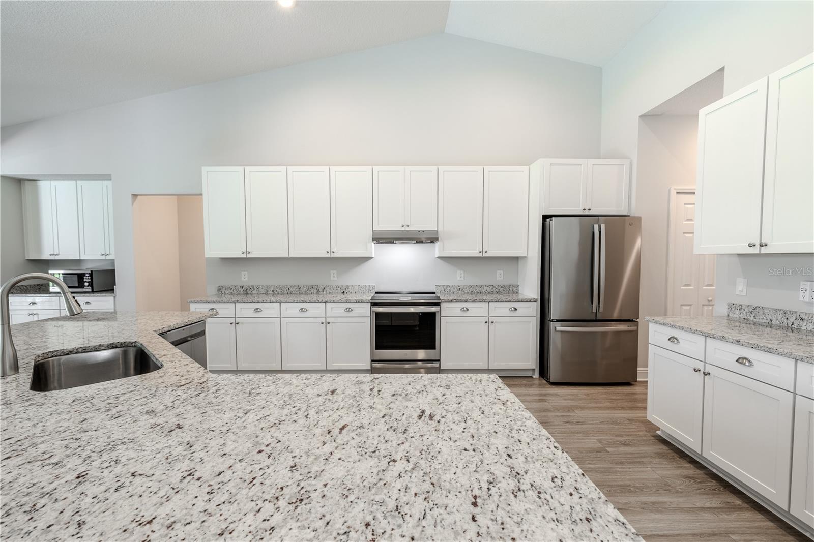 Crisp white cabinetry pairs beautifully with stainless steel appliances, including a built-in microwave and smooth-top range.