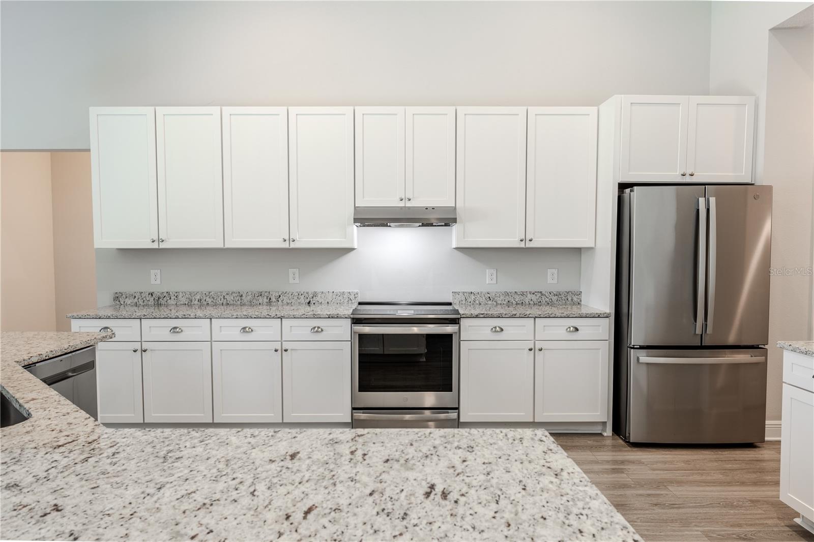 Crisp white cabinetry pairs beautifully with stainless steel appliances, including a built-in microwave and smooth-top range.