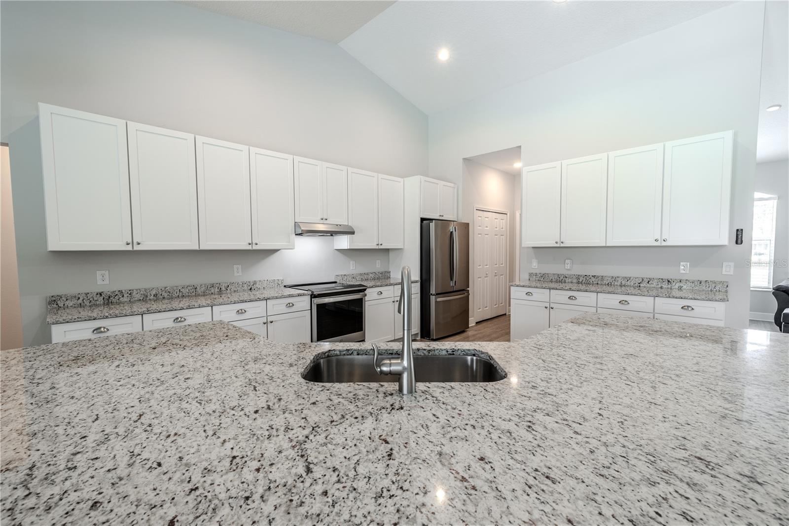 This beautifully designed kitchen features an expansive granite-topped island with an undermount sink and breakfast bar seating, perfect for meal prep and casual dining.
