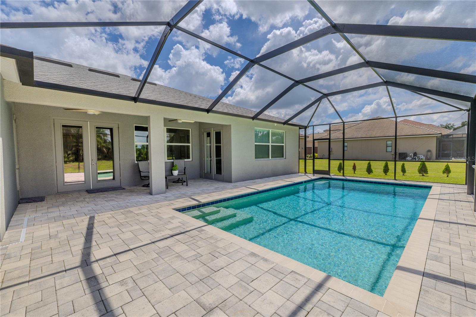 Enjoy year-round outdoor living in the sparkling screened-in pool, surrounded by an expansive paver deck ideal for lounging or entertaining. The enclosure offers unobstructed views of the lush, tree-lined backdrop while keeping the area comfortable and pest-free. Whether swimming laps or relaxing in the sun, this inviting space provides the perfect private retreat.