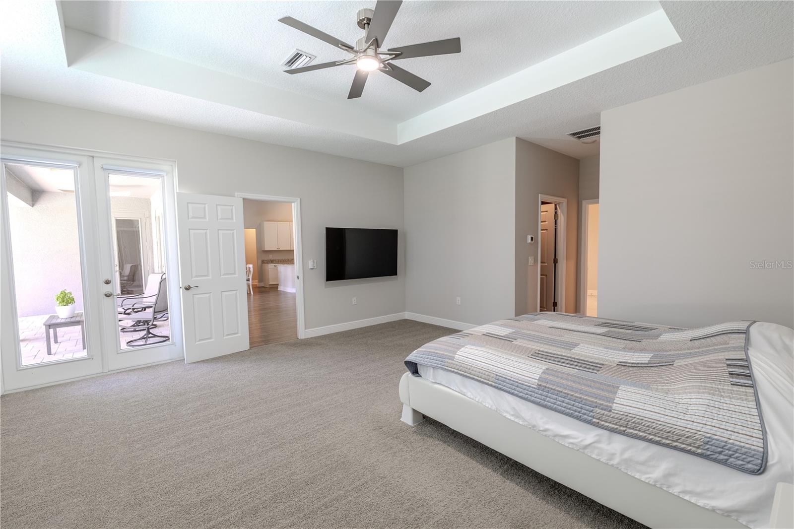 The primary bedroomgives you private access to the screened lanai through double glass doors, creating a seamless indoor-outdoor connection. The tray ceiling with modern fan enhances the room’s airy feel, while plush carpeting adds comfort. Conveniently located off the main living area, the suite includes direct access to the en-suite bath and nearby walk-in closet.