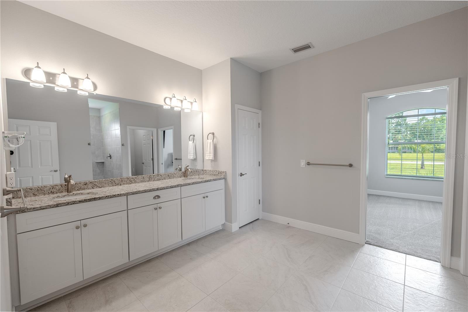 Primary bathroom: Sleek brushed nickel fixtures and modern lighting add a touch of elegance, while the neutral tile flooring creates a bright, clean look. Direct access to the primary bedroom enhances convenience and flow.