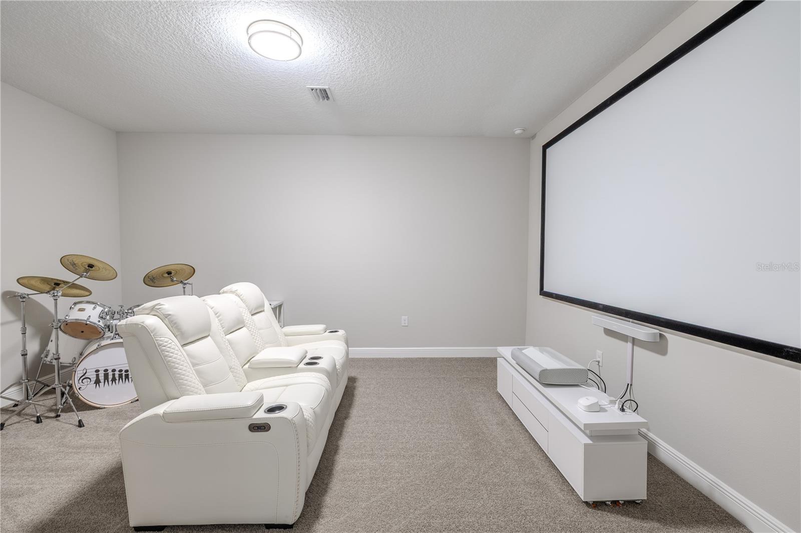 The media room  features plush carpeting, soft neutral wall tones, and a flush-mounted ceiling light that provides even illumination. Its spacious, enclosed layout makes it a versatile area that can easily be customized to suit different needs.