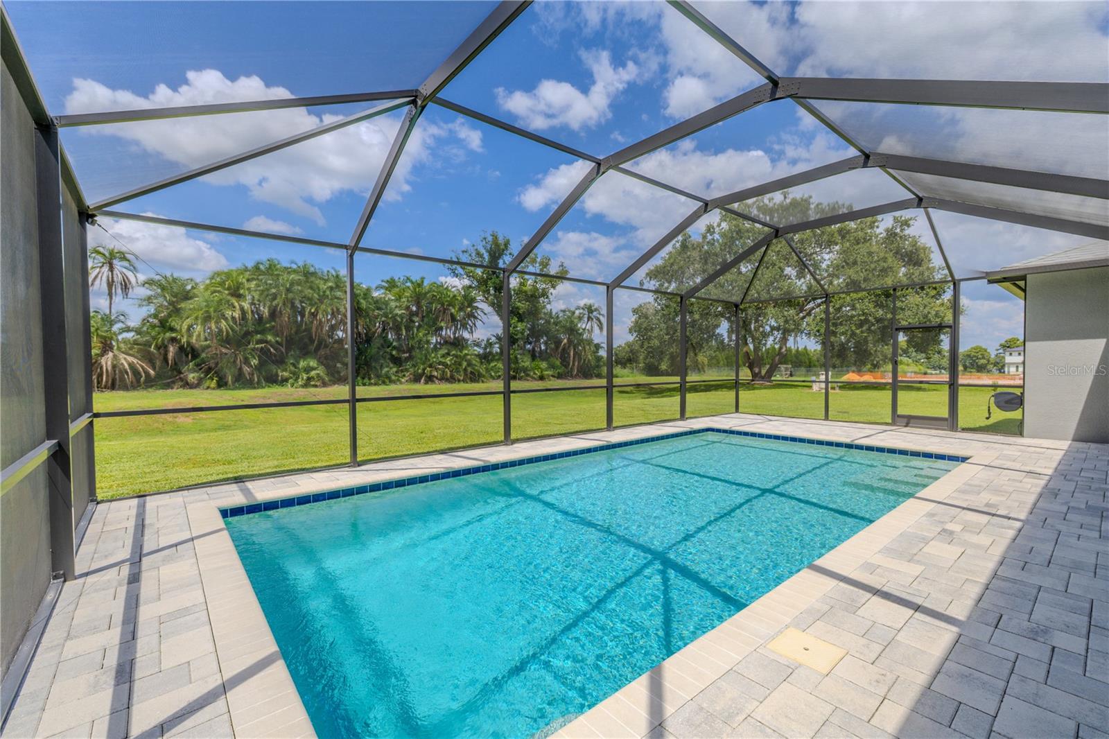 his in-ground gunite/concrete pool is designed for both style and functionality, featuring a screen enclosure that allows for uninterrupted enjoyment while keeping debris and pests out.