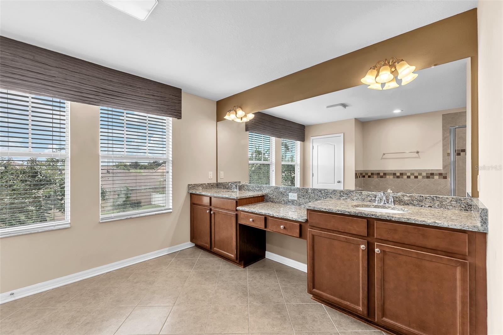 Large vanity with two sinks and a makeup vanity with granite.