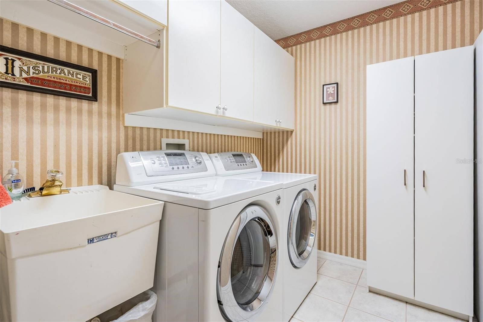 Walk-in laundry room with plenty of additional storage options and utility sink