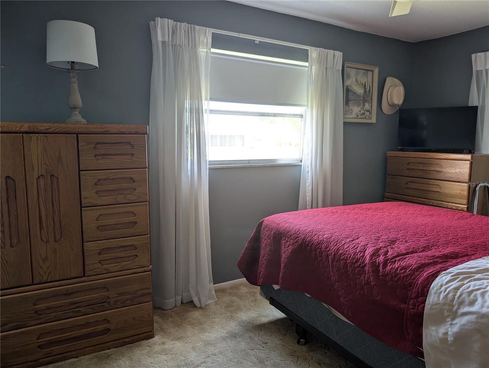 Carpeted guest bedroom offers ceiling fan, large window and access to Florida room.