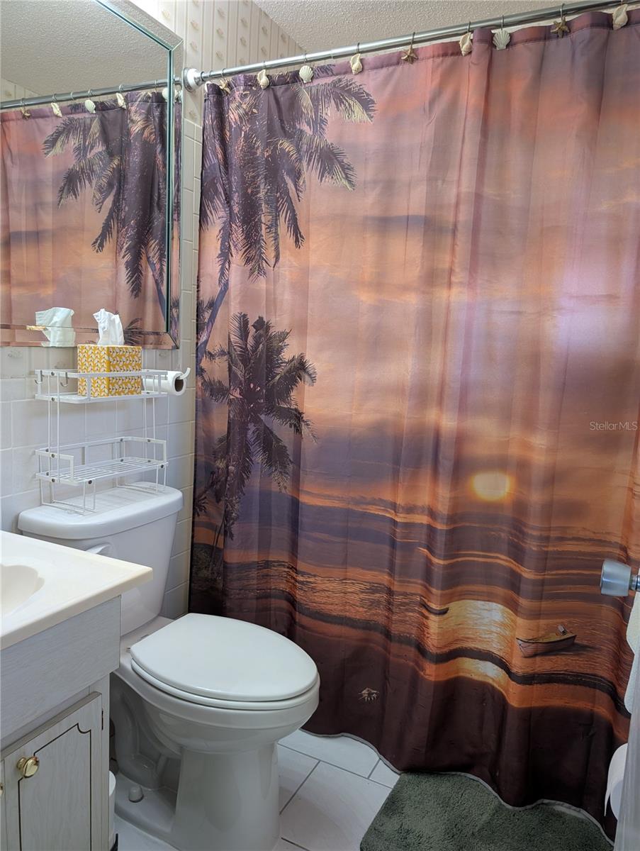 Guest bath offers tub w/shower,  tile floor, comfort commode and vanity.