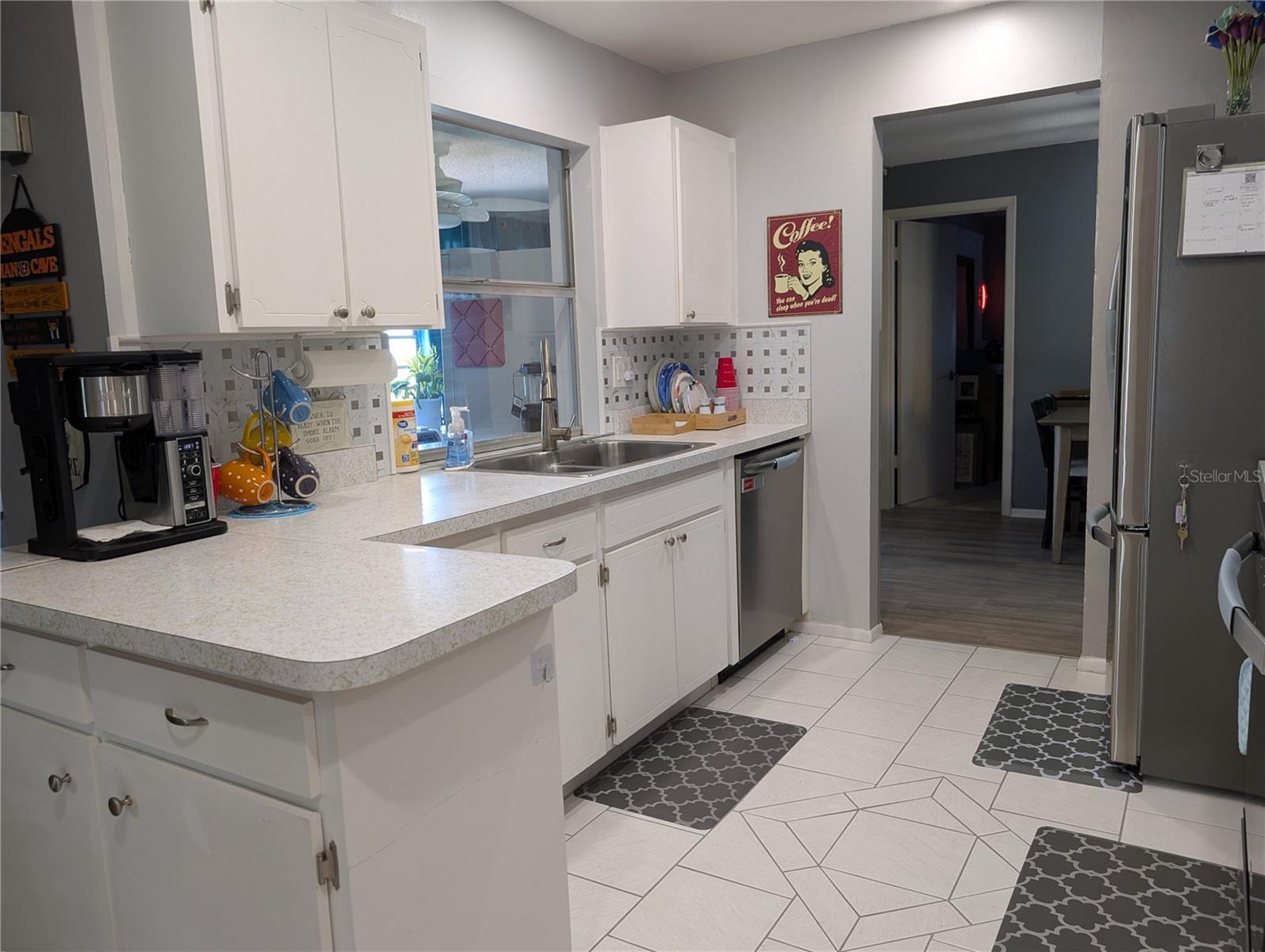 Kitchen features tile floor, pass thru window to Florida room, Frigidaire stainless steel dishwasher (2022), great counterspace and cabinet storage.