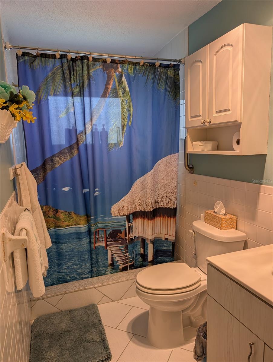 Primary bath offers walk in shower, comfort commode, long vanity and tile flooring. Walk in closet is located in bathroom.