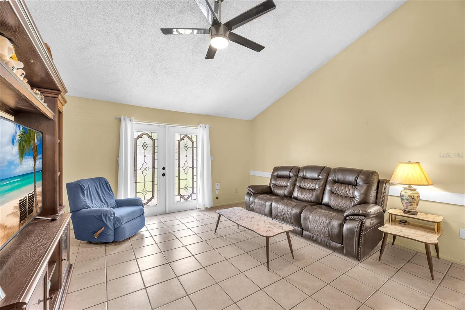 The living room boasts a cathedral ceiling and beautiful leaded glass French doors that allow abundant natural light to fill the space.