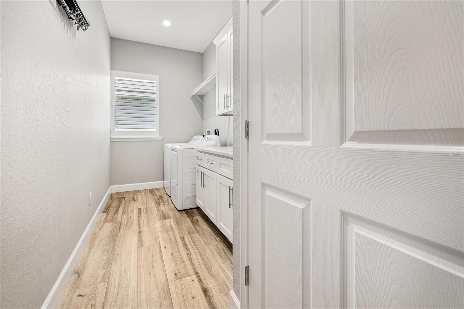 Large laundry room with built in sink & cabinets with quartz countertops. Lots of storage!