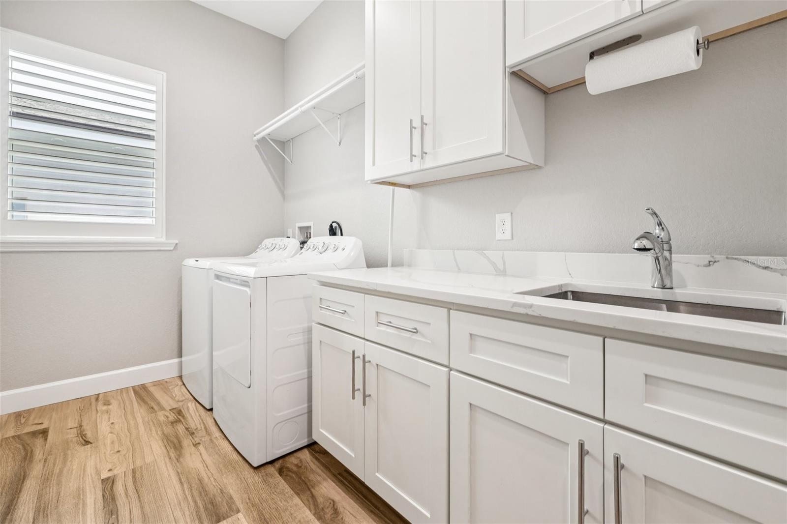 Large laundry room with built in sink & cabinets with quartz countertops. Lots of storage!