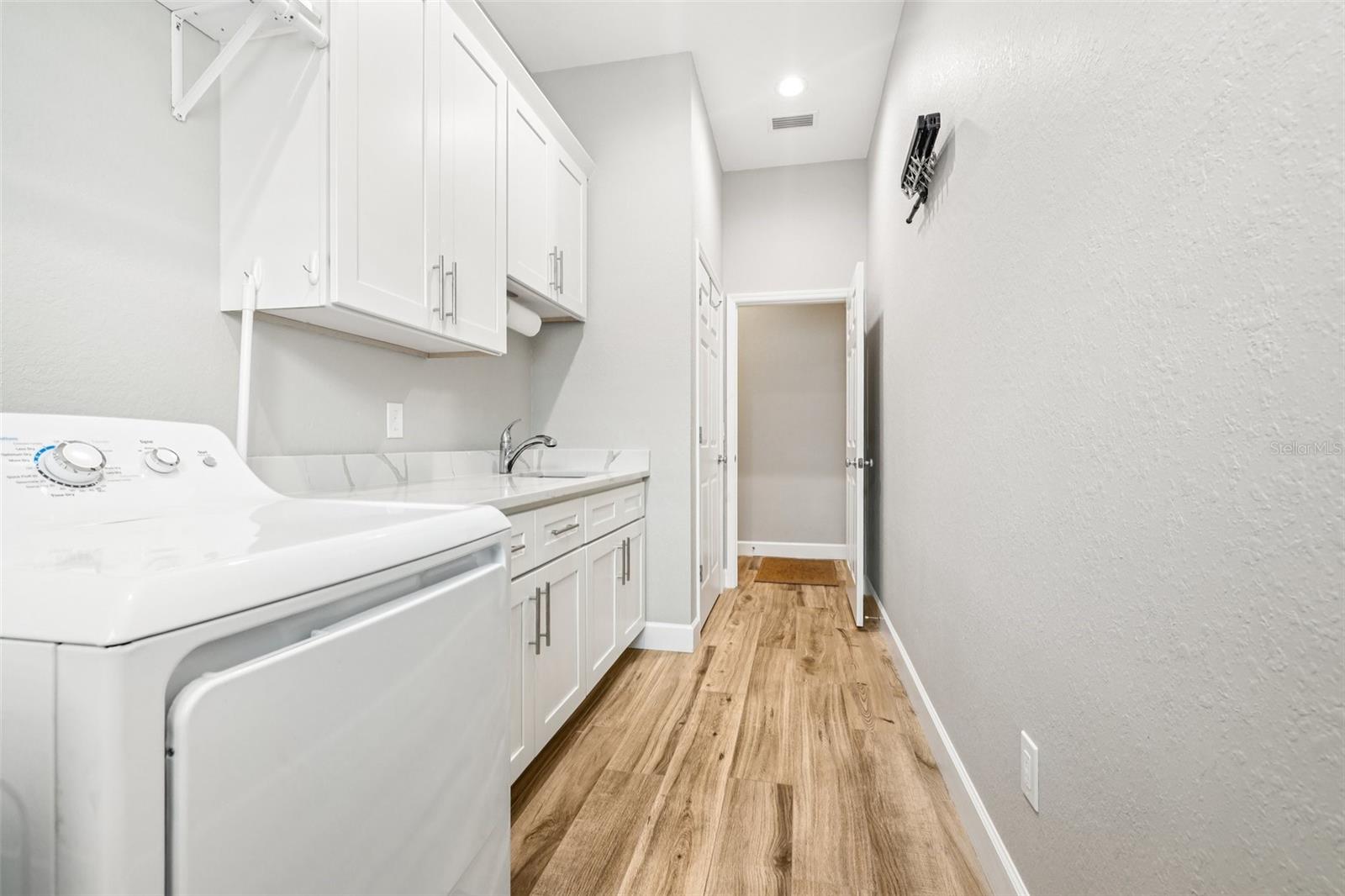 Large laundry room with built in sink & cabinets with quartz countertops. Lots of storage!