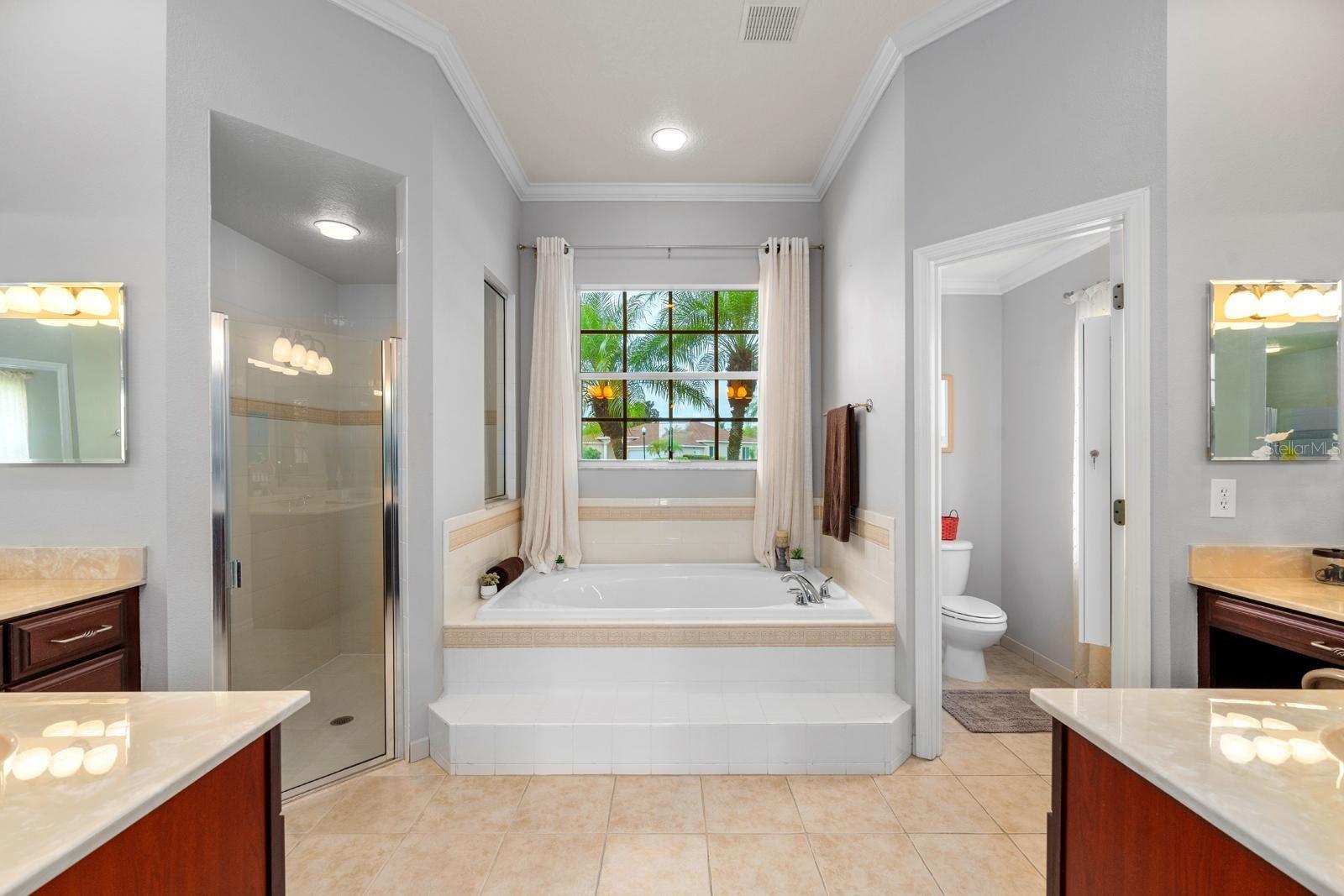 The primary ensuite features crown molding, a walk-in shower, large soaking tub, private water closet, and two separate vanities with sinks and extensive counter space!