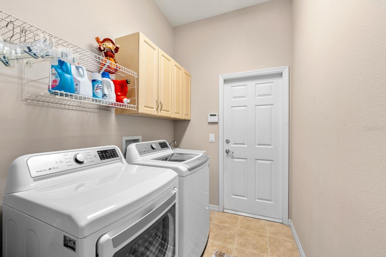 The laundry room features a utility sink, storage cabinets and shelving.  The dryer vent has just been cleaned out.  The door leads to the garage.