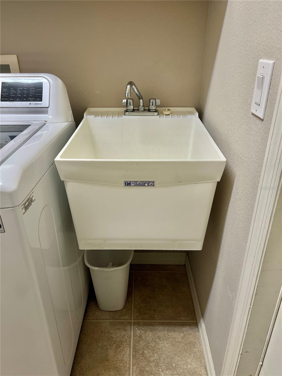 The laundry room features a utility sink....and storage cabinets and shelving.  The door leads to the garage.