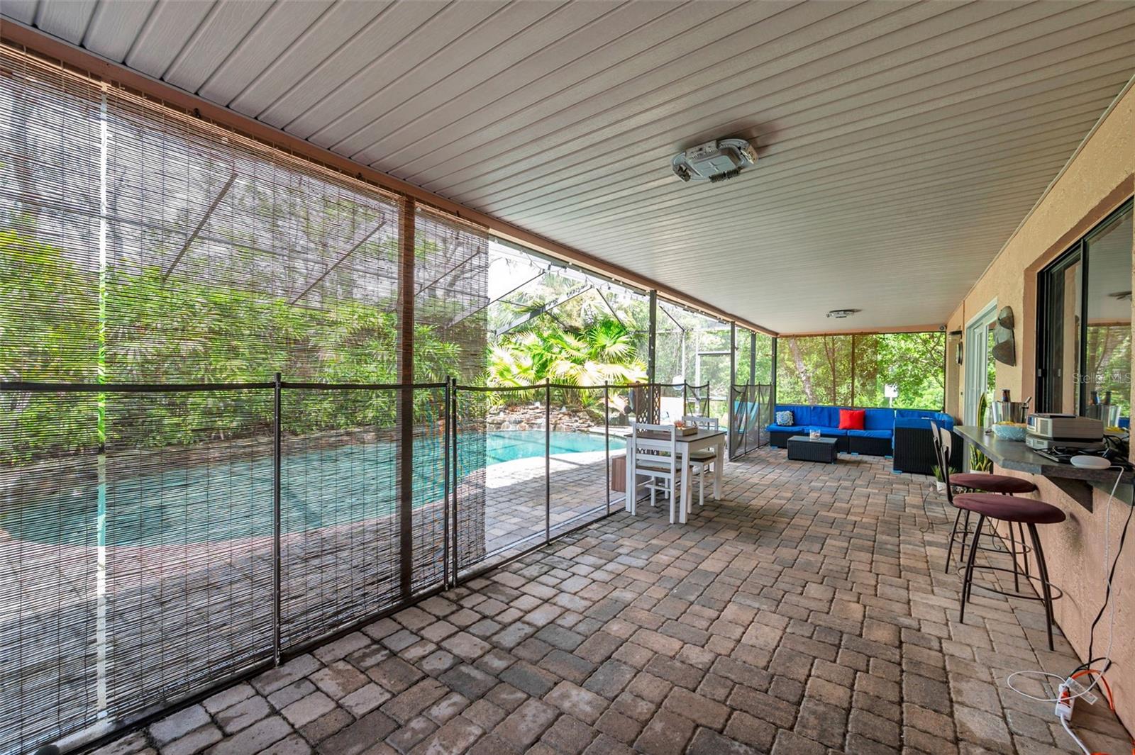 Screen enclosed pool with rock waterfall, pavers, and huge covered patio