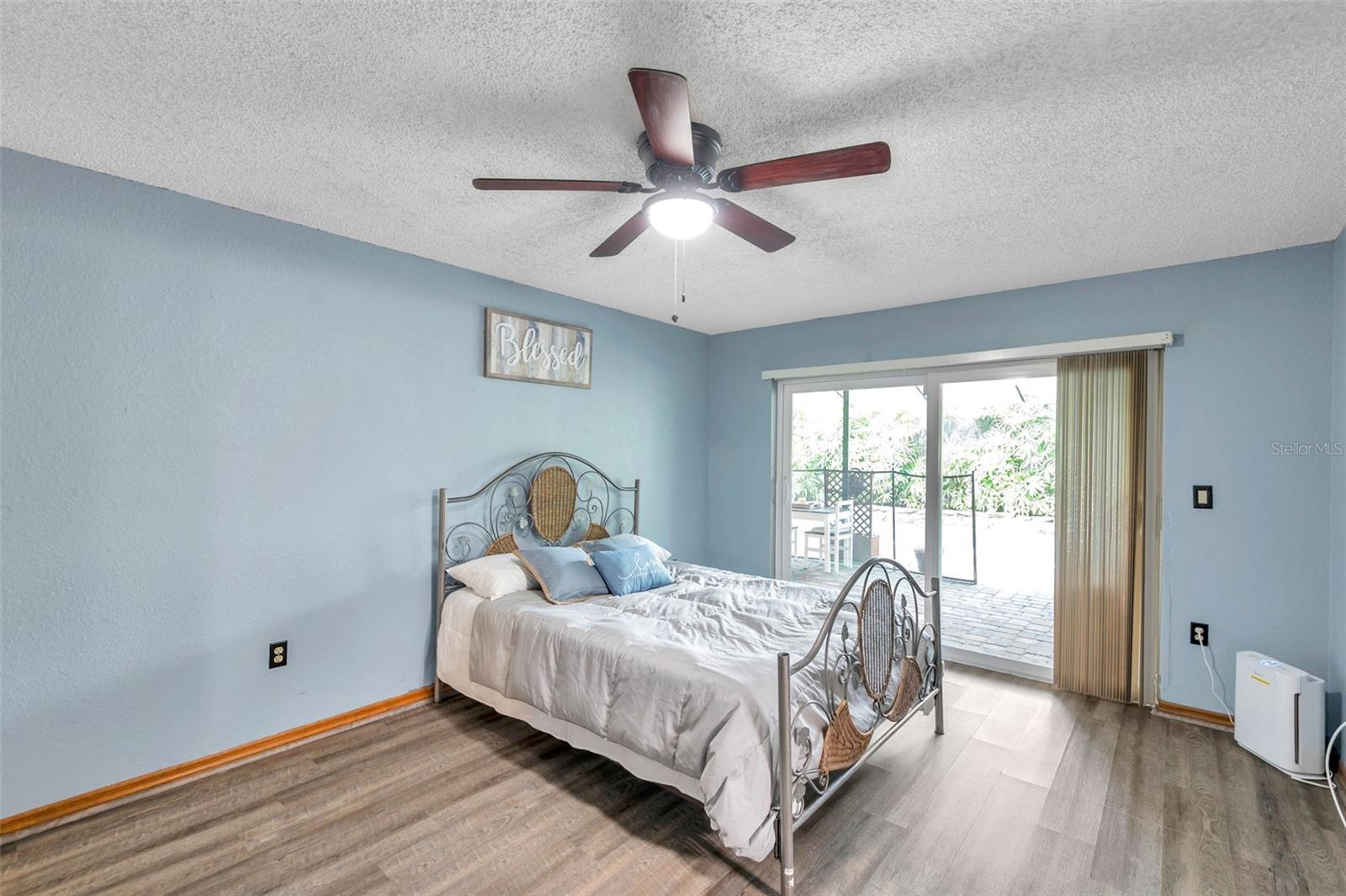 Primary bedroom features a Sliding Glass Doors to the Pool/Patio, Ensuite Bathroom, Ceiling Fan, and large Walk-In Closet