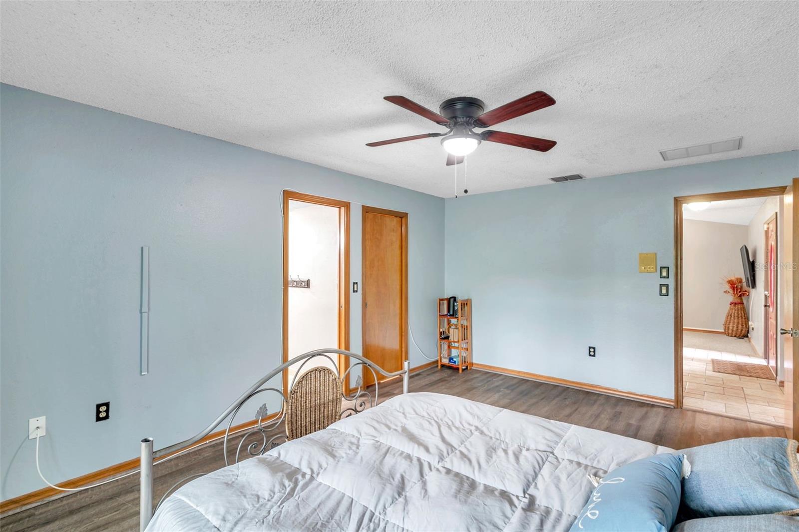 Primary bedroom features a Sliding Glass Doors to the Pool/Patio, Ensuite Bathroom, Ceiling Fan, and large Walk-In Closet
