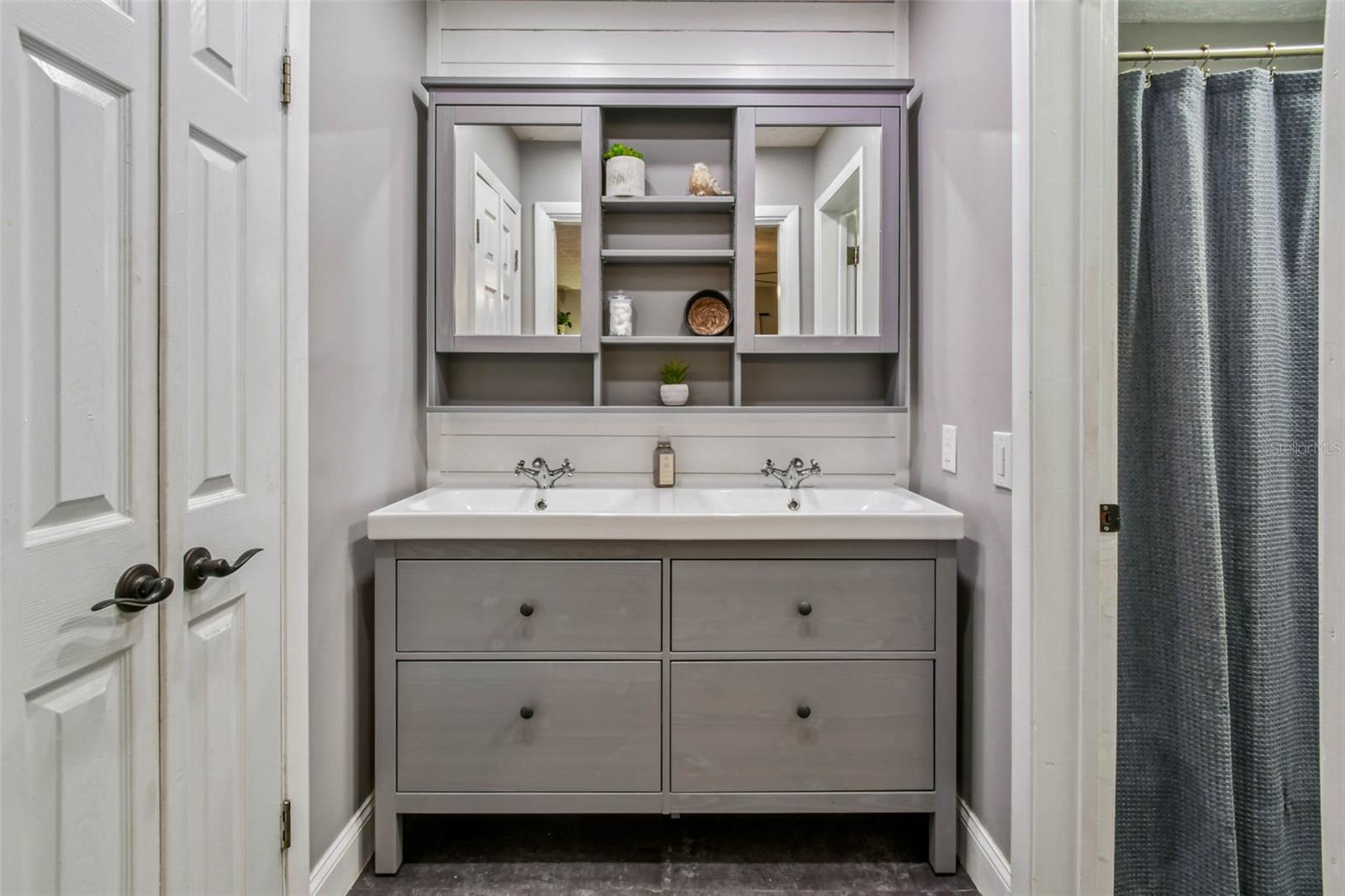 The walk-in closet is to the left of the double vanity in the primary en suite bathroom.