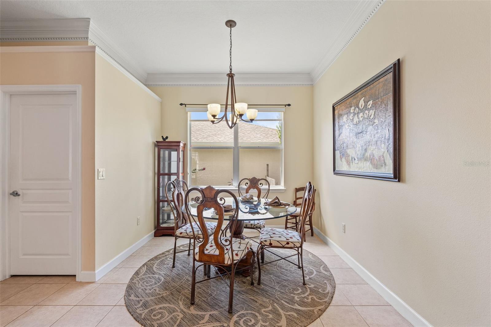 Cozy dining nook with tile flooring, crown molding, and a large window for natural light.