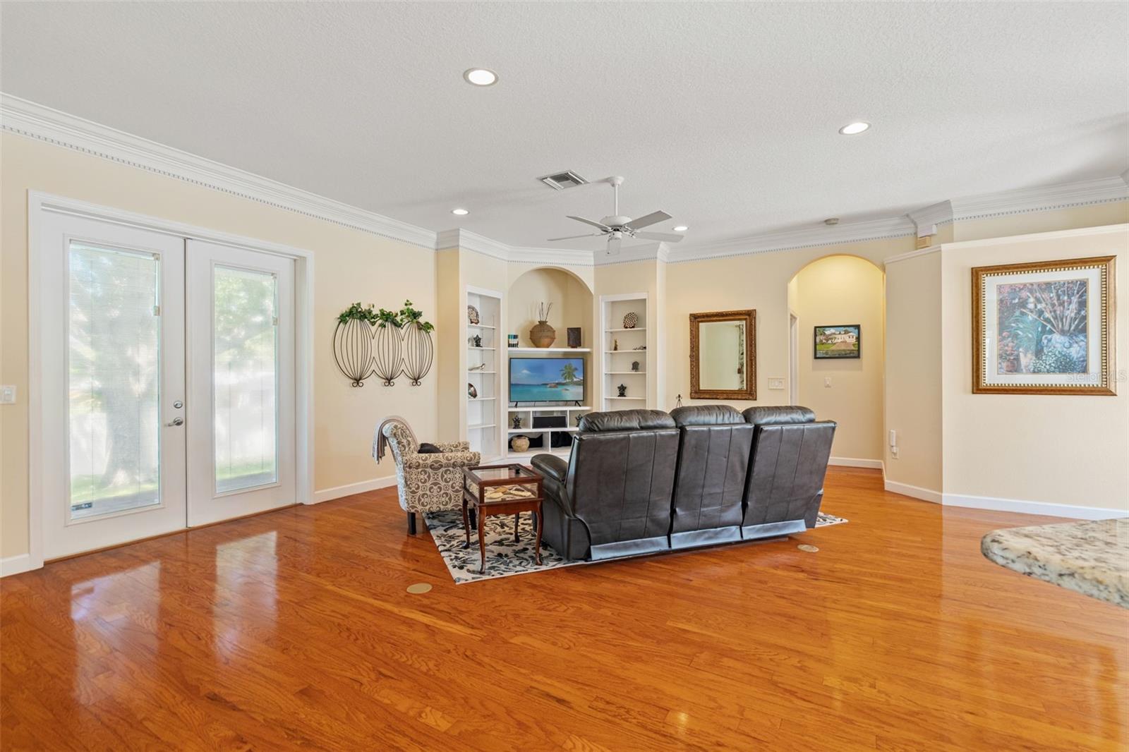 Bright family room with French doors opening to the backyard, accented by custom built-in shelving.