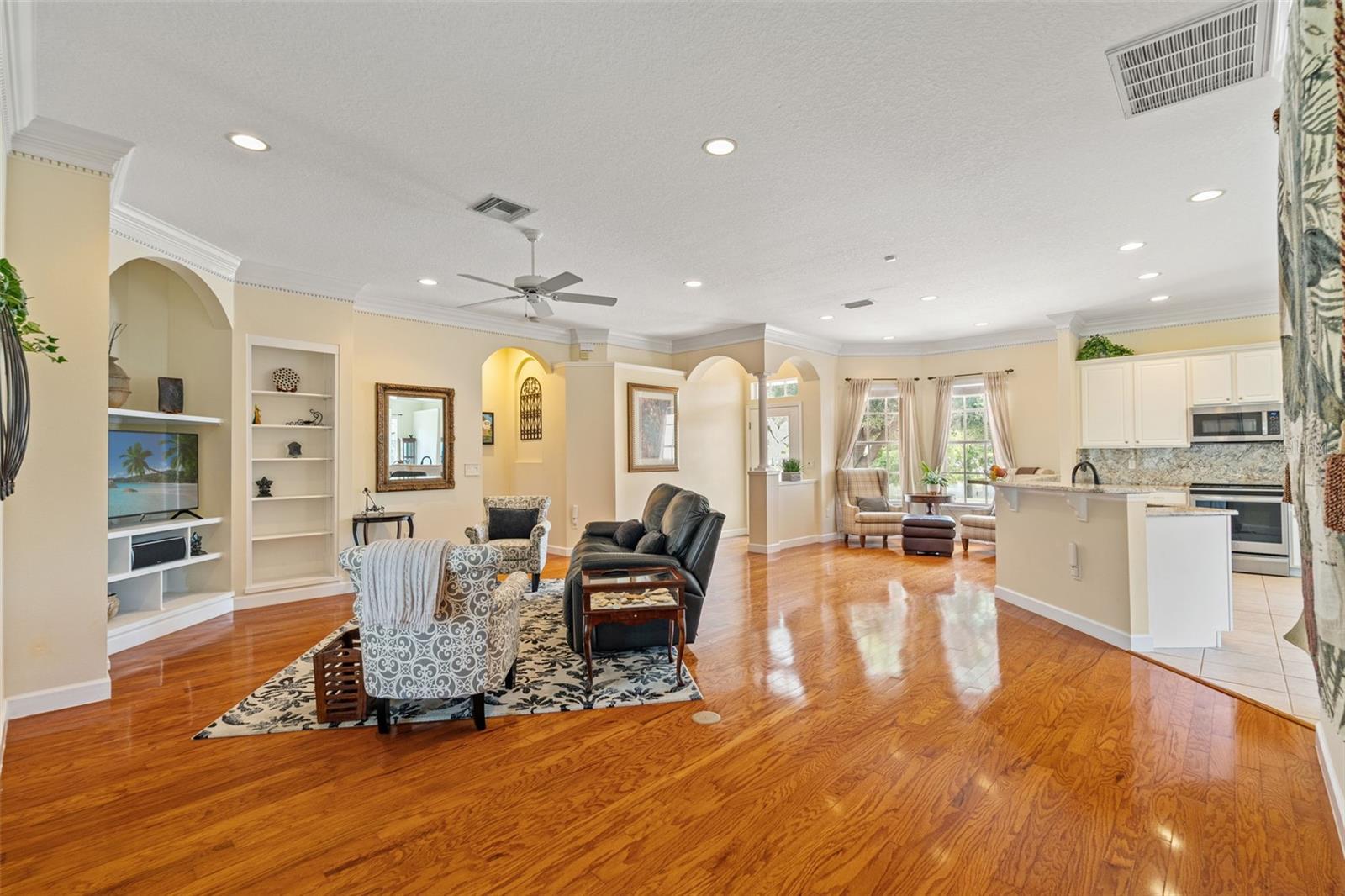 View of the open-concept living area showcasing wood floors, recessed lighting, and arch details.