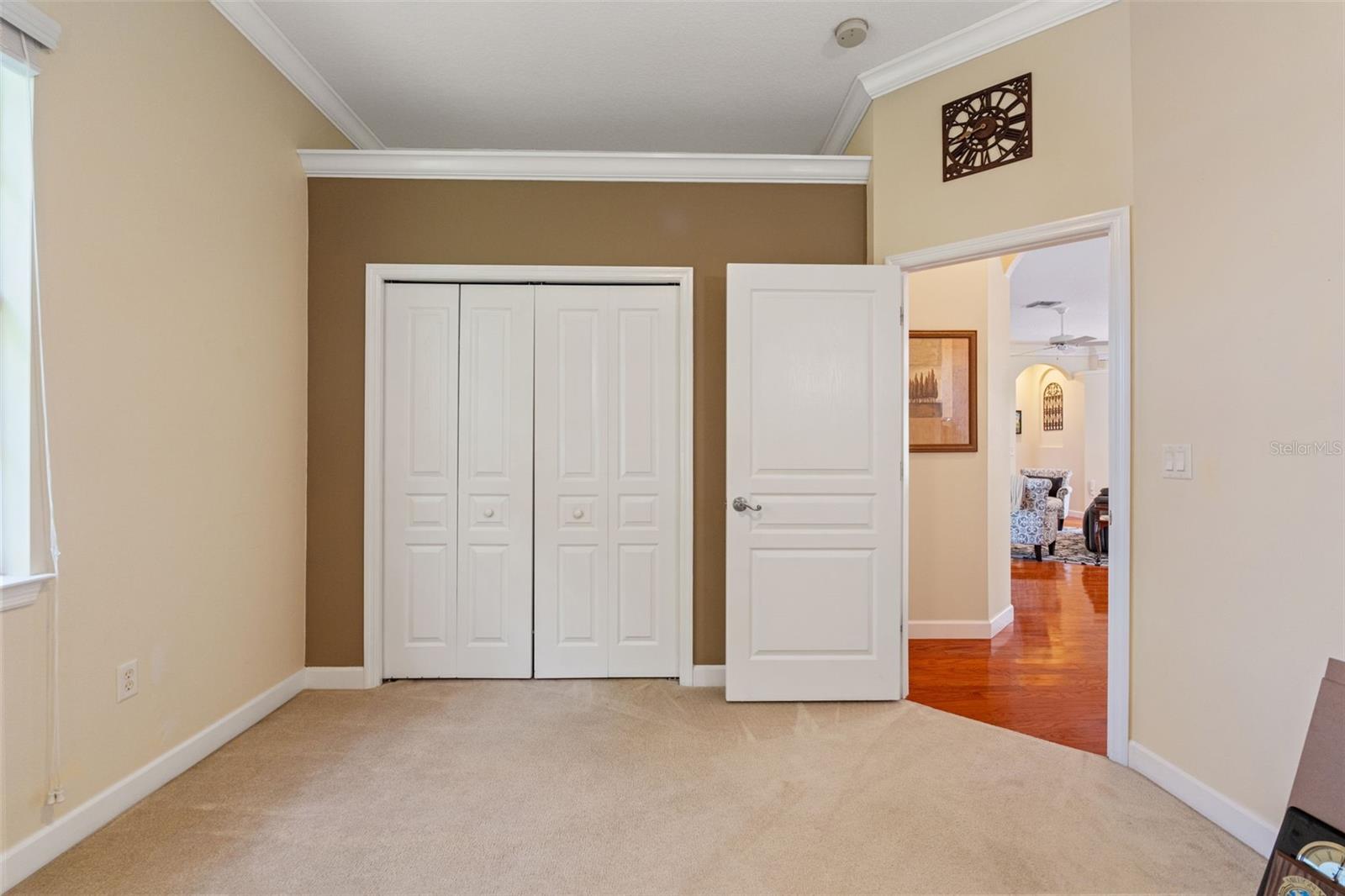 Another shot of the 3rd bedroom with neutral carpet, crown molding, and double-door closet.