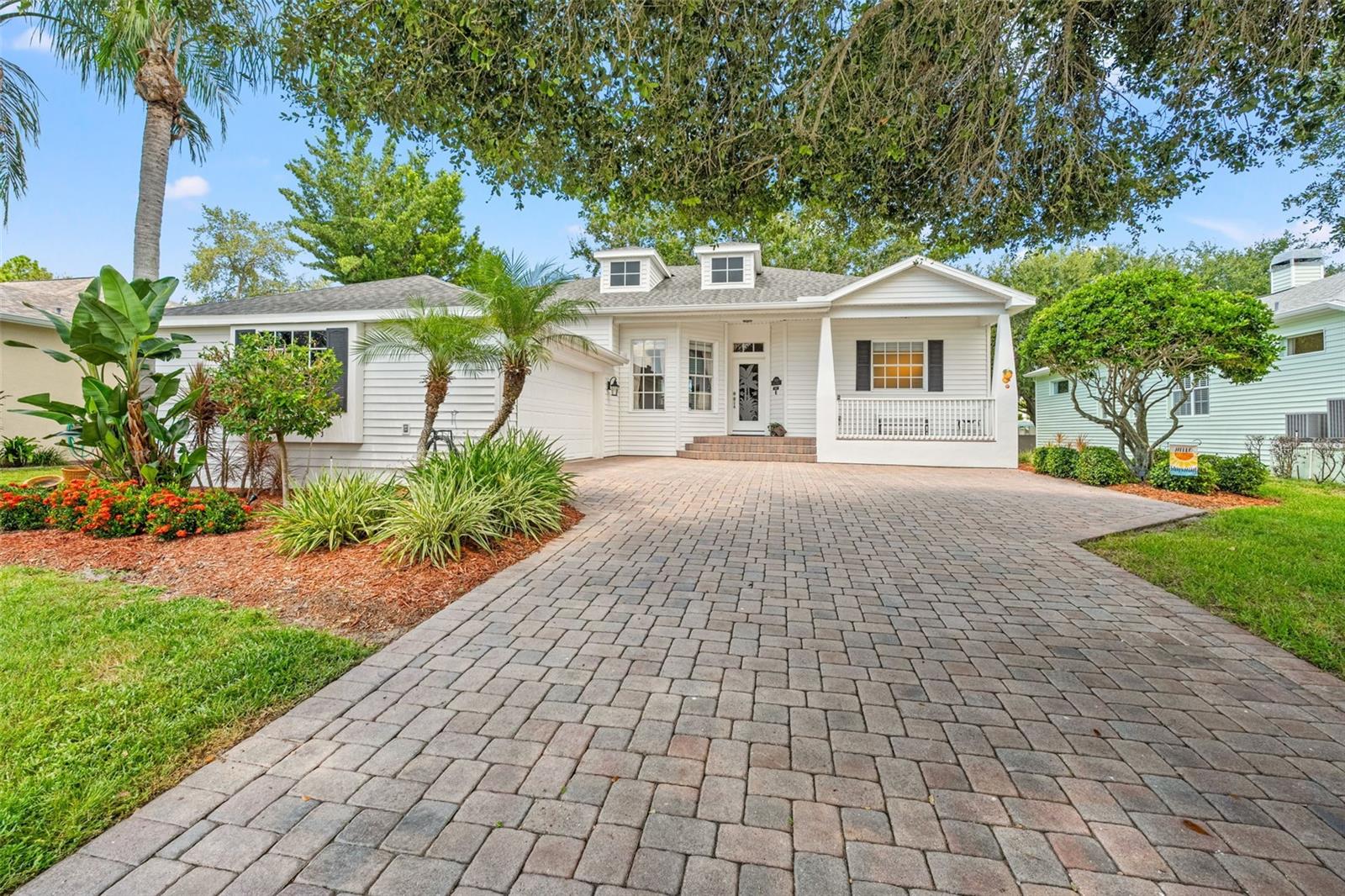 Side perspective shows the spacious driveway, lush greenery, and landscaped entry.