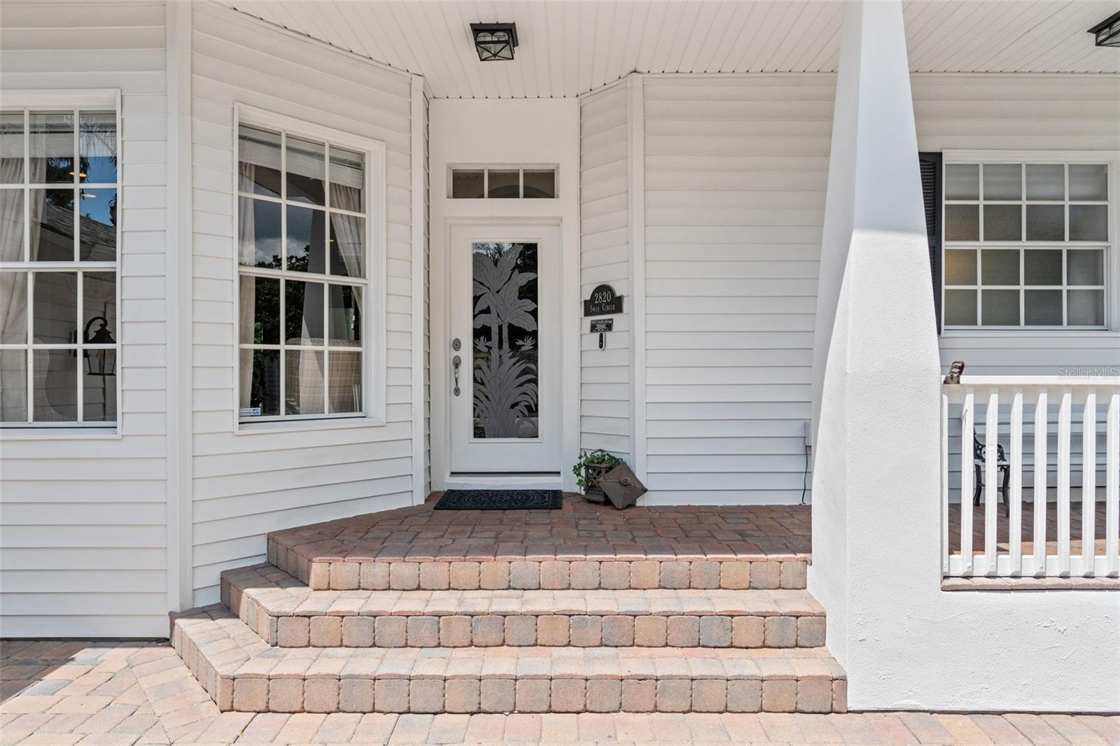 A brick paver walkway leads to the welcoming front entry, complete with a decorative glass door and transom window.