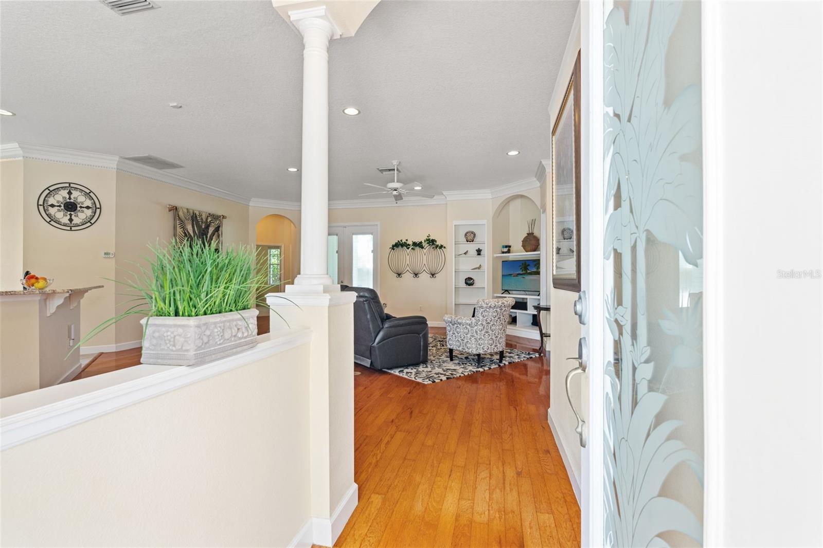 Step inside to a bright entry with decorative columns and hardwood floors that open into the main living space.