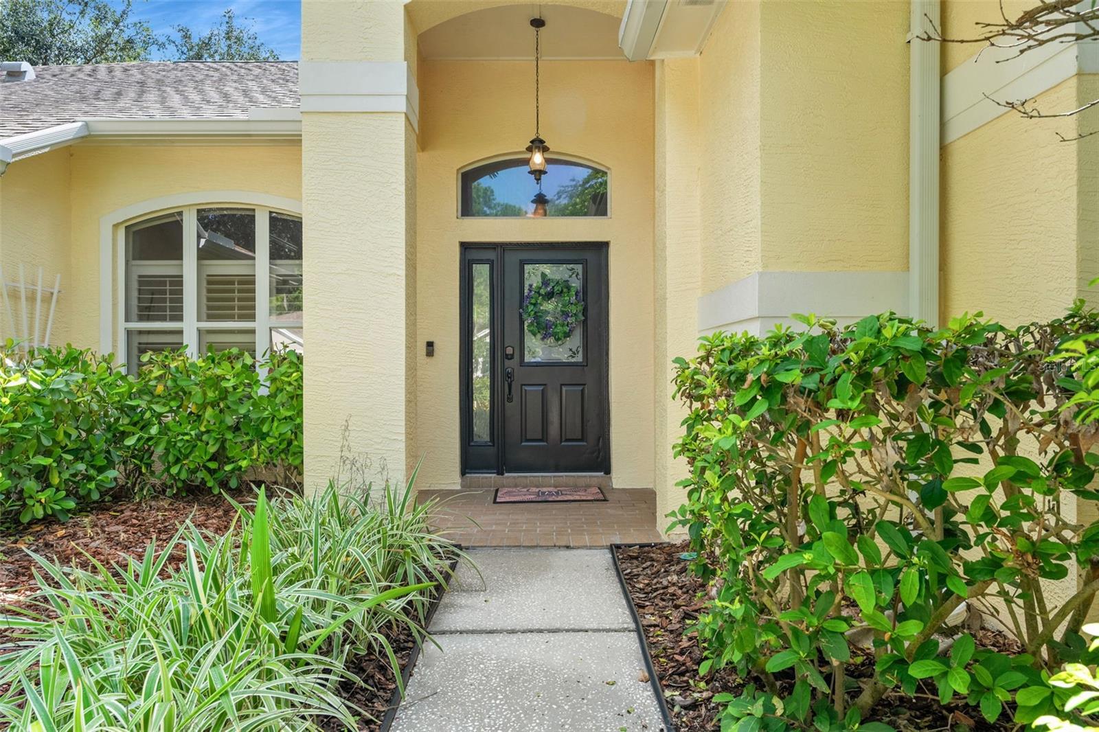 Welcoming front entry with a decorative black door, overhang, and landscaping that frames the entrance nicely.