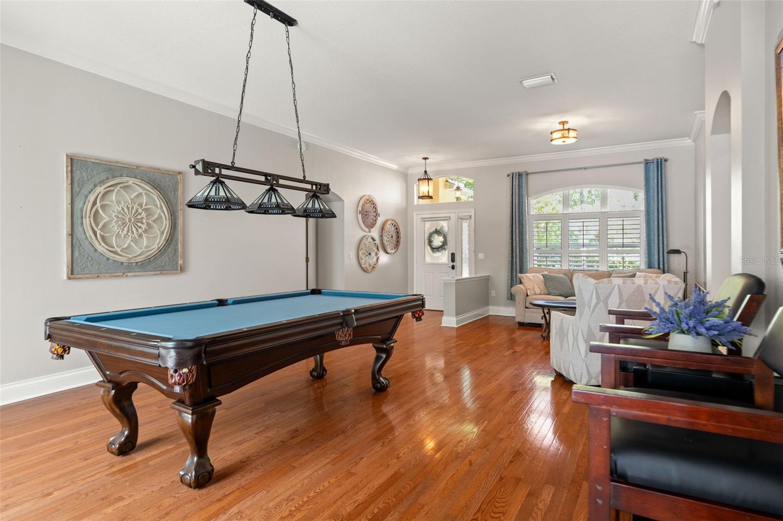 A wide-angle view capturing the layout from the game room (dining room) toward the entry and sitting area, emphasizing flow, function, and comfort in one expansive space.