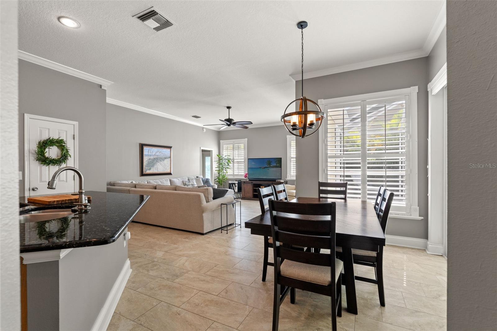 Light and airy dining area with tile flooring, plantation shutters, and a stylish pendant light fixture. Positioned just off the kitchen for easy entertaining.