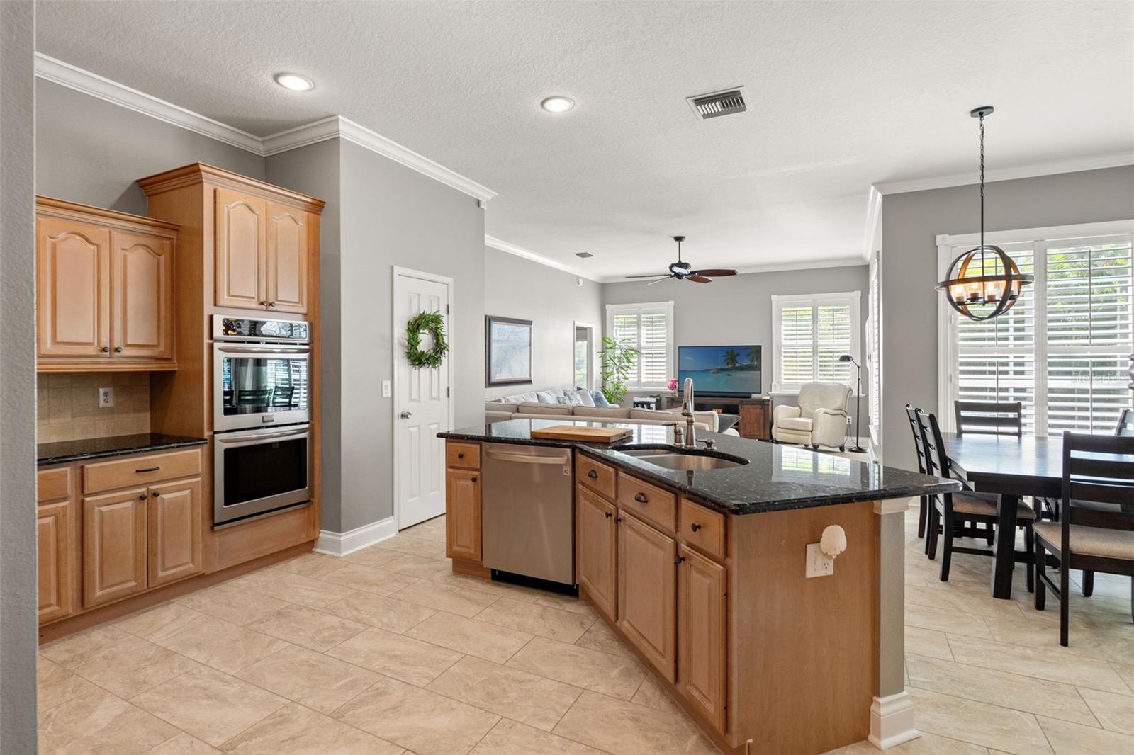 The expansive granite island includes a prep sink, dishwasher, and bar seating, all overlooking the open-concept family room for seamless entertaining.