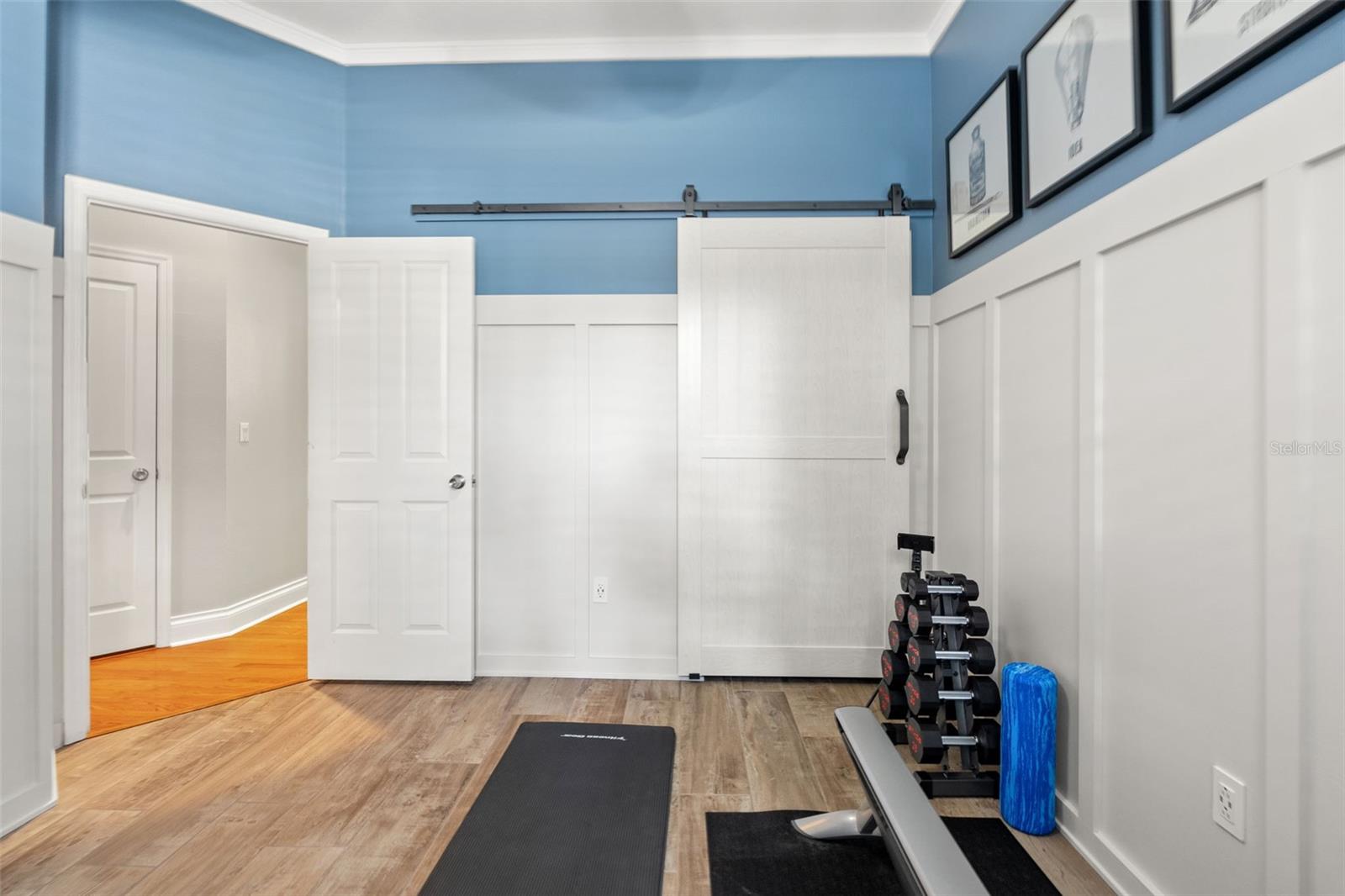 The 2nd guest room with stylish wainscoting, durable flooring, and a sliding barn door offers the perfect space for workouts at home or a guest room.