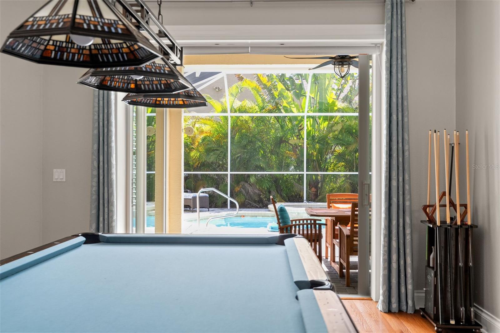 A view from the game (dining) room reveals direct access to the lanai and pool, making this space ideal for entertaining and casual relaxation.