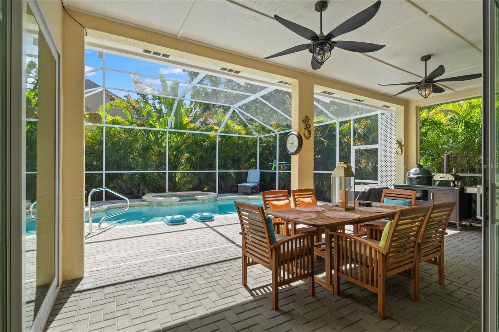 The resort-style heated pool and spa are framed by lush tropical foliage, offering privacy and serenity in a fully screened enclosure.