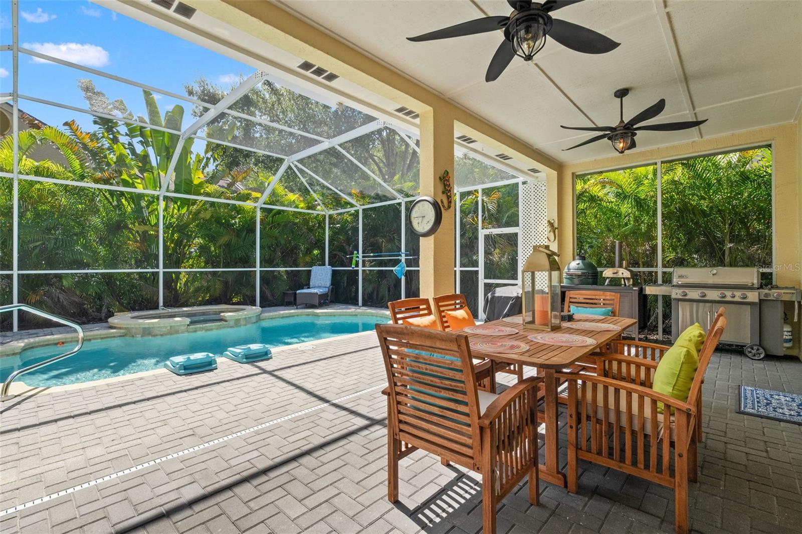 This inviting pool and raised spa are beautifully lit for evening enjoyment, surrounded by privacy landscaping and enclosed in a screened cage.
