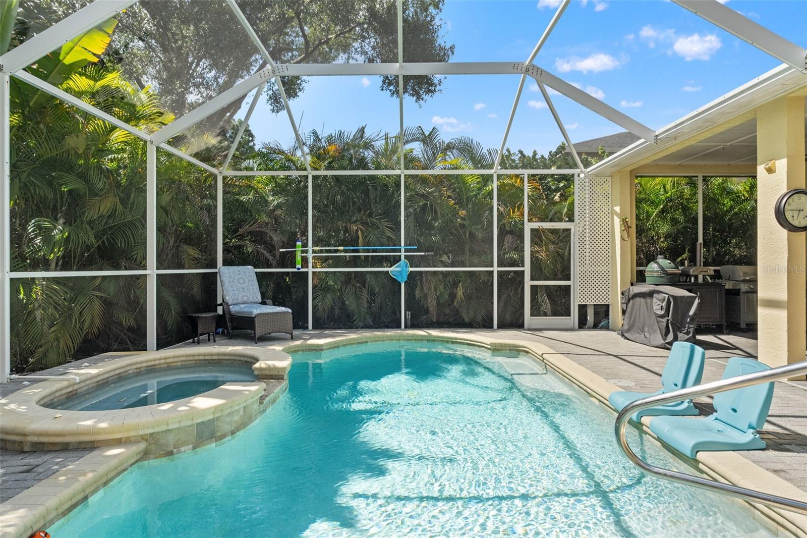 Crystal-clear waters shimmer under the screened enclosure, with built-in tanning ledge chairs and raised spa offering the ultimate relaxation zone.
