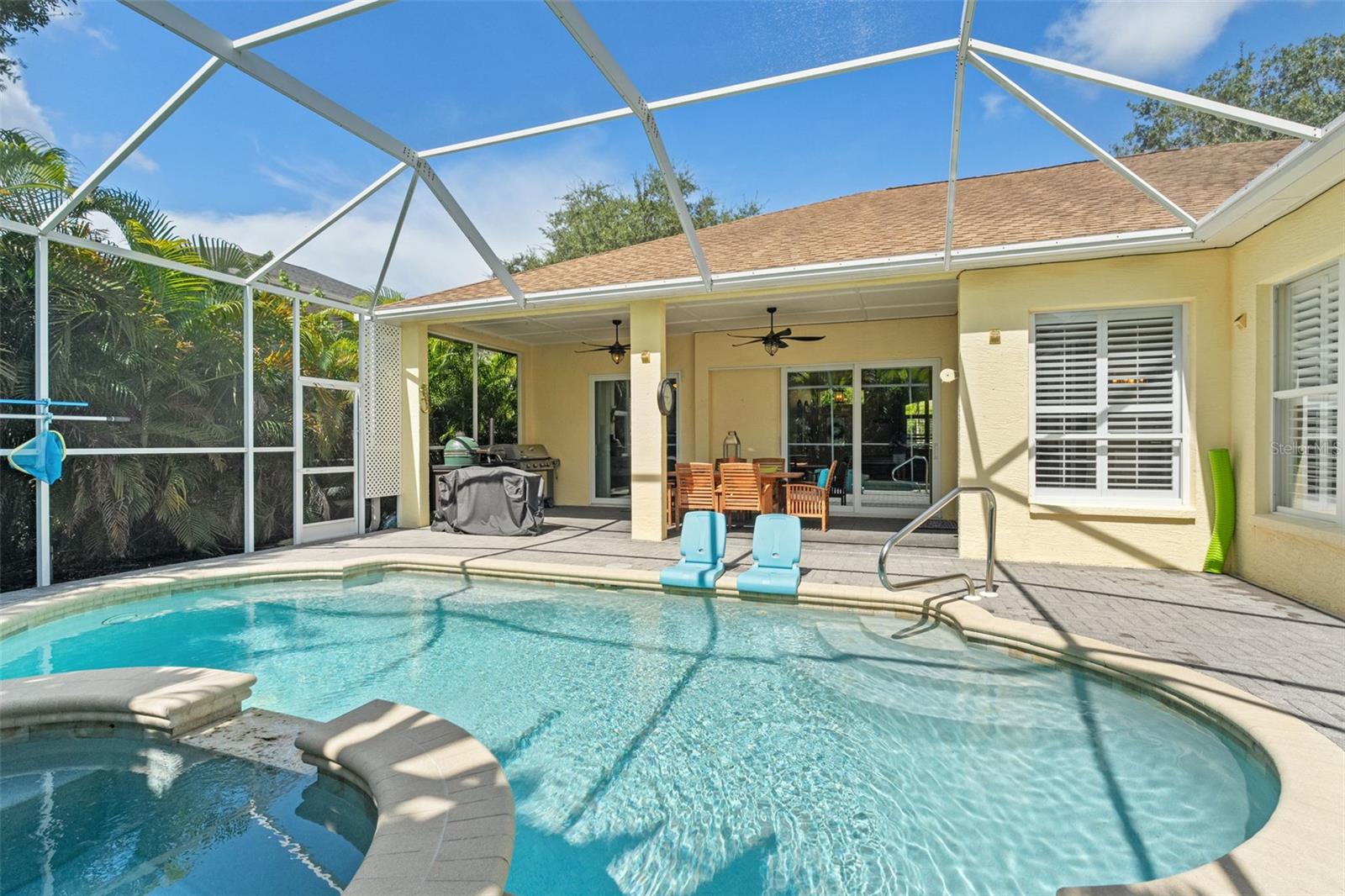 Spacious pool deck with lounging and dining areas connects to the indoor living spaces via sliding glass doors—ideal for effortless entertaining.