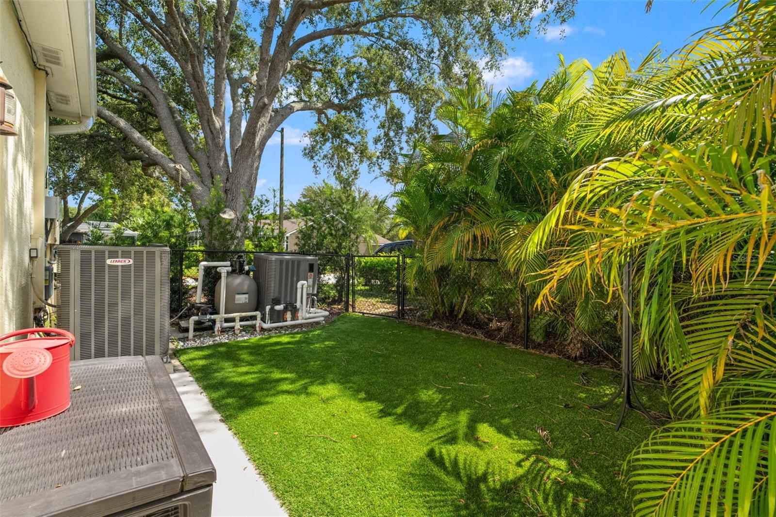 Functional fenced side yard with turf, pool equipment, and dual HVAC units, discreetly tucked away yet easily accessible.