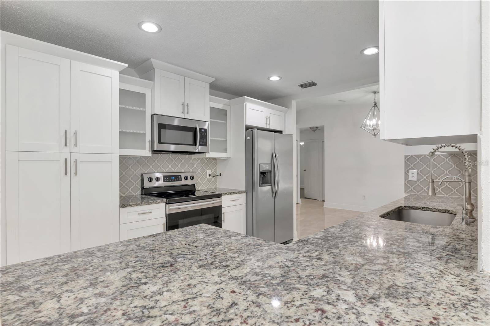 Spacious granite island with tall, soft-closing cabinets providing both elegance and ample storage.