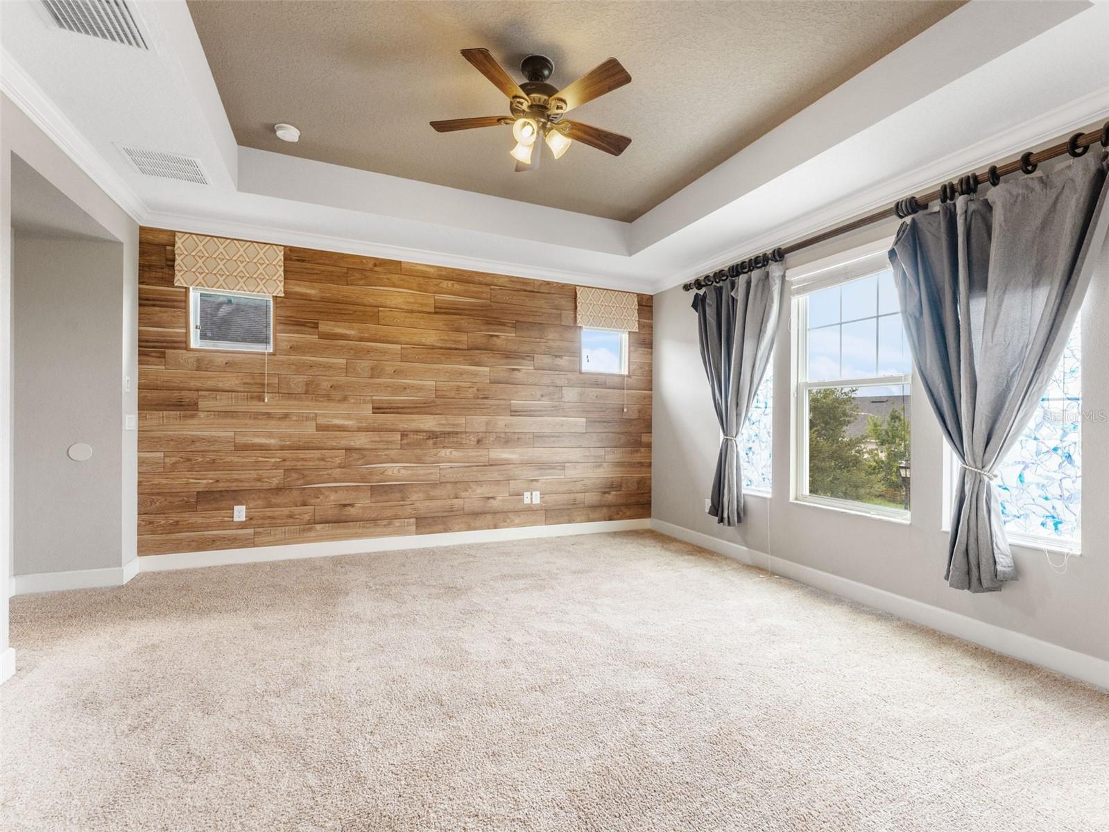 Master bedroom with Tray Ceilings, and Beautiful Wooden Accent Wall!